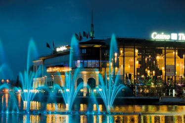 Photo représentant le Casino Barrière d'Enghien-les-Bains la nuit, avec des jeux d'eau et de lumière